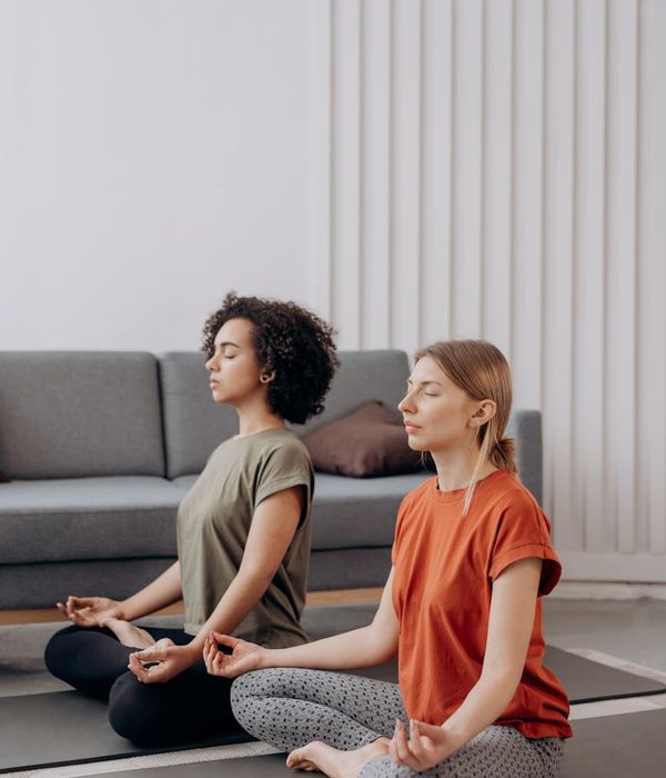Woman in a calm yoga pose in a room with soft, natural light.